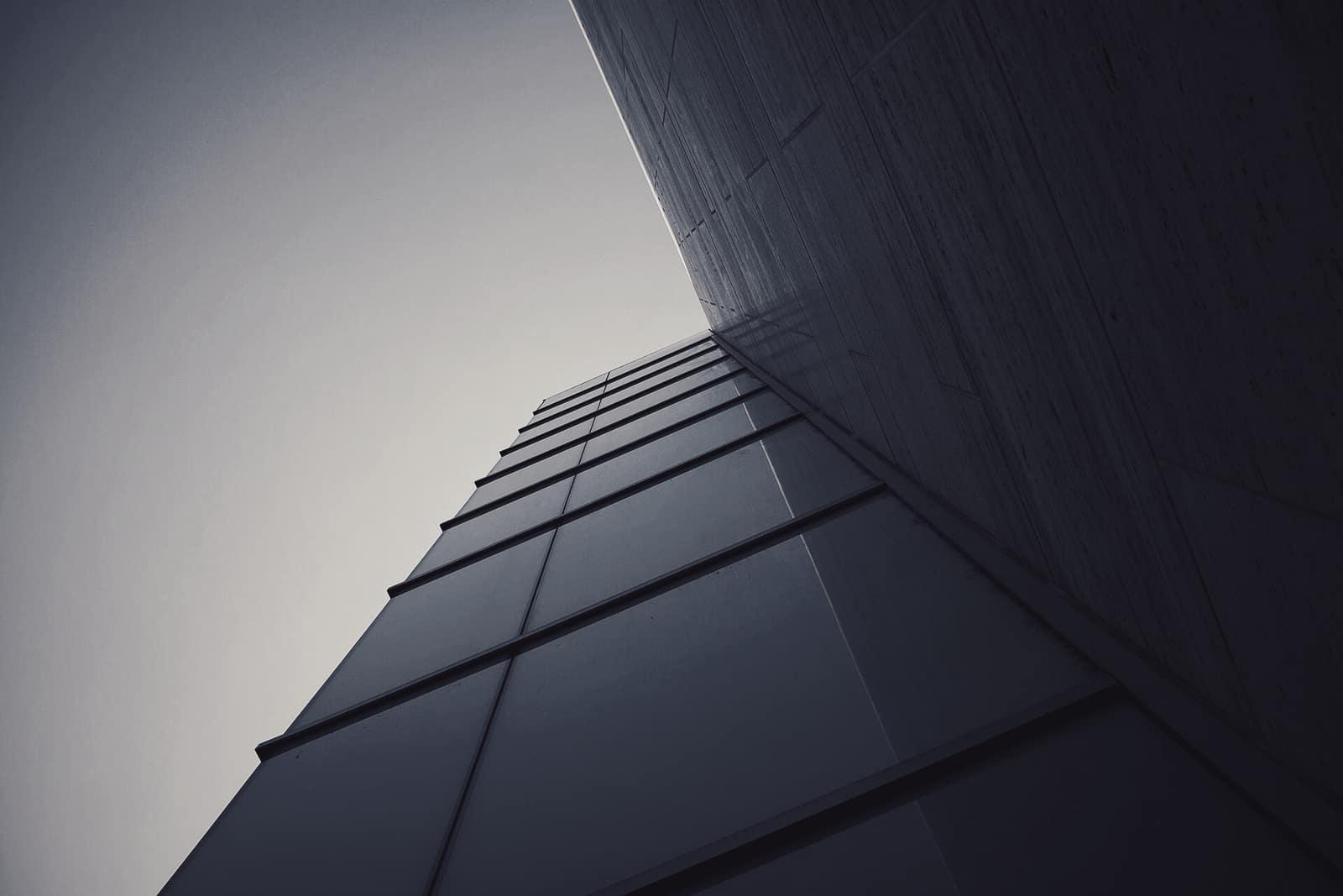 The corner of a blue glass office building against the sky
