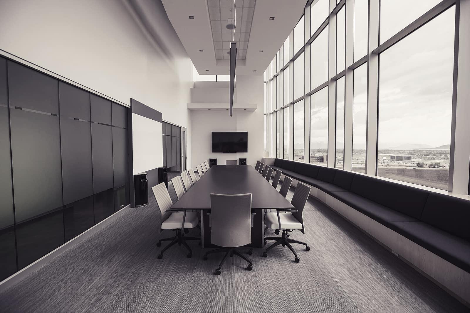 A long boardroom table beside floor-to-ceiling windows