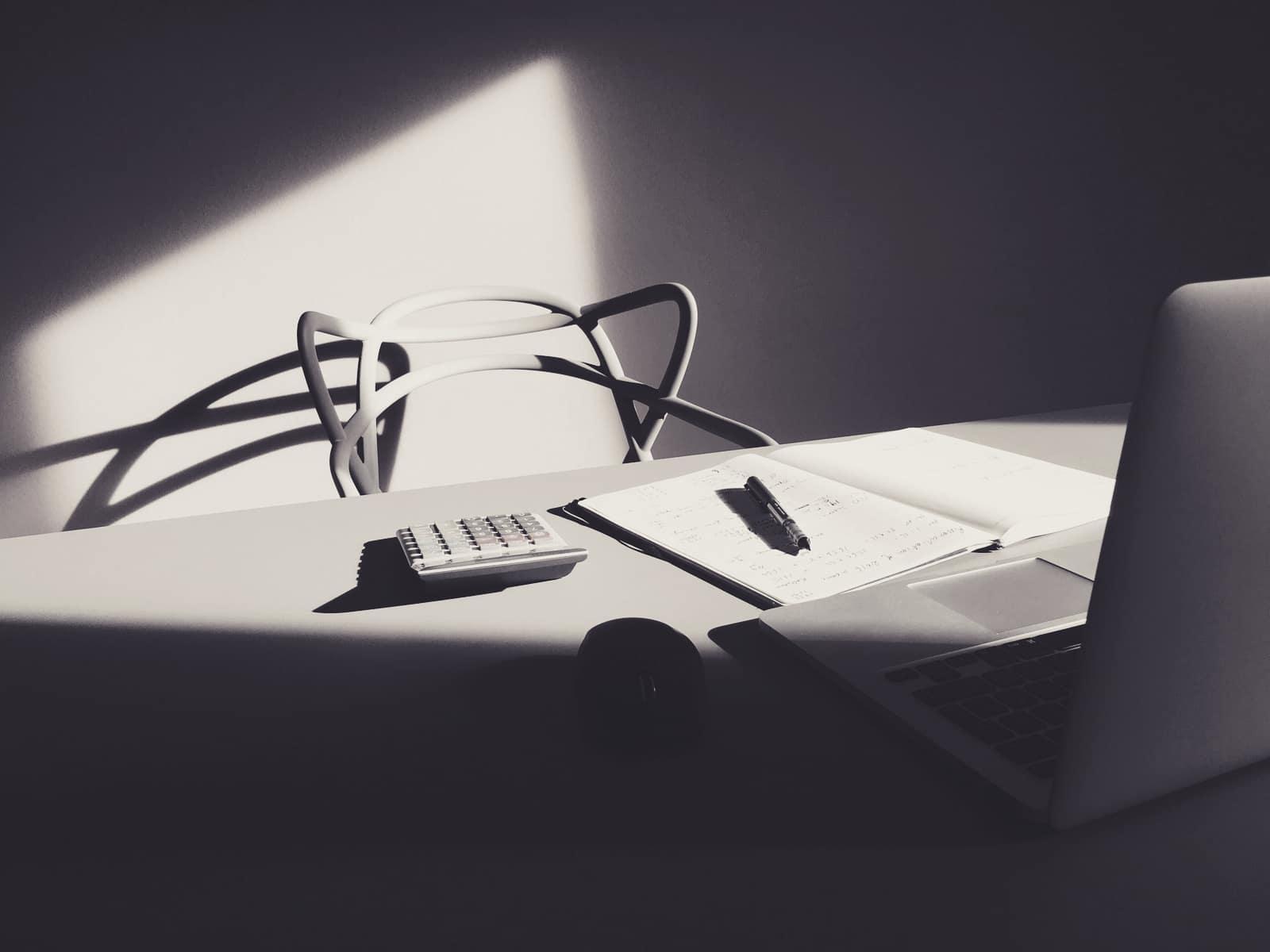 A desk with a laptop, calculator and papers